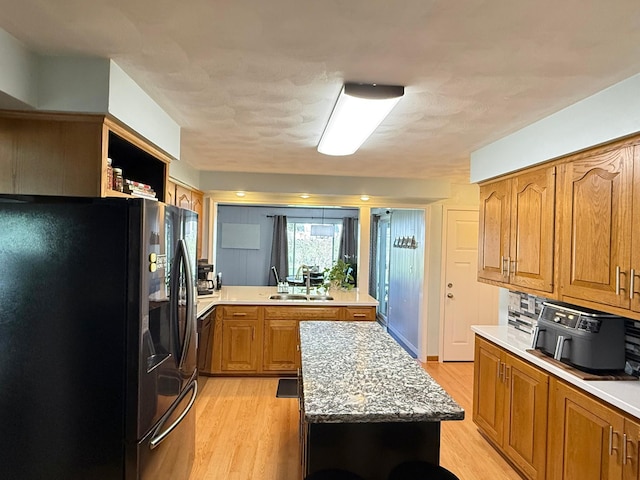 kitchen featuring freestanding refrigerator, light wood-type flooring, and light countertops
