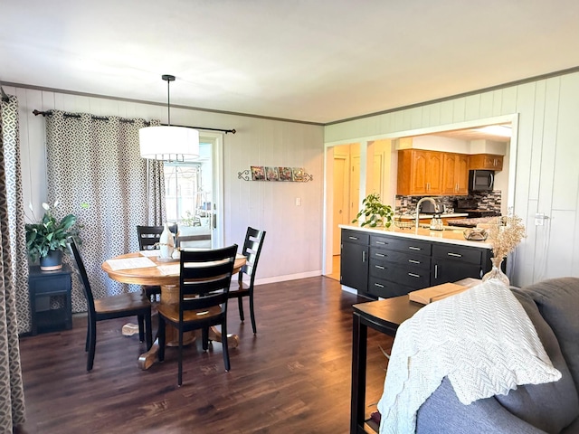 dining area featuring dark wood-type flooring, crown molding, and baseboards