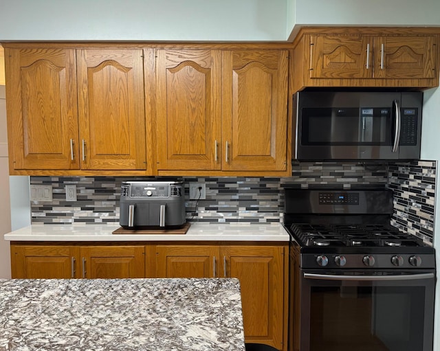 kitchen with appliances with stainless steel finishes, backsplash, and brown cabinets