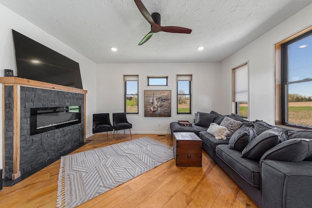 20355 Cedar Lake Trl, Shieldsville Twp, MN 55052 - living area with a glass covered fireplace, light wood-style floors, a ceiling fan, recessed lighting, and baseboards