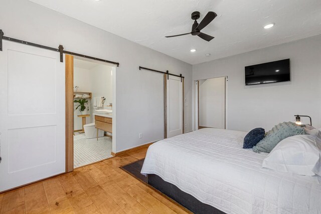 20355 Cedar Lake Trl, Shieldsville Twp, MN 55052 - bedroom featuring a barn door, light wood-style floors, recessed lighting, ensuite bathroom, and a ceiling fan