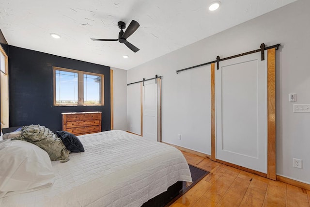 20355 Cedar Lake Trl, Shieldsville Twp, MN 55052 - bedroom with a barn door, light wood-type flooring, recessed lighting, baseboards, and ceiling fan