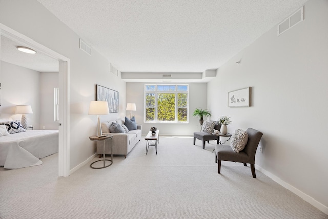 sitting room with carpet, a textured ceiling, and baseboards