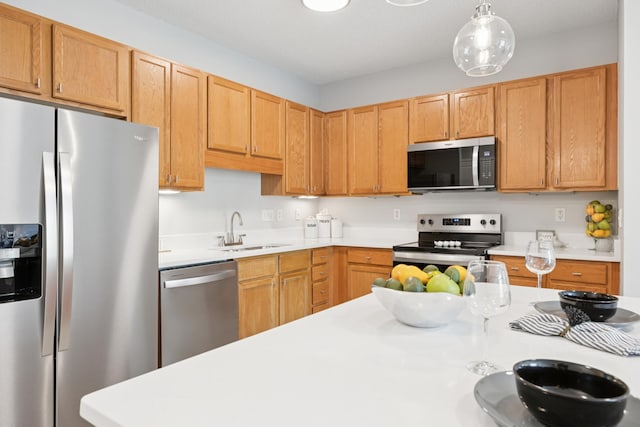 kitchen featuring stainless steel appliances, a sink, light countertops, and decorative light fixtures