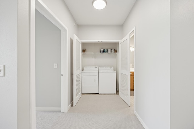 washroom featuring washing machine and clothes dryer, light colored carpet, and baseboards
