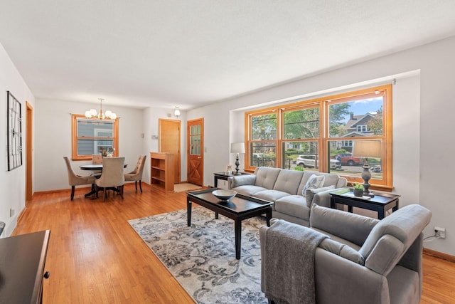 living room with a chandelier, light wood-style flooring, and baseboards