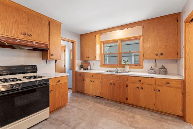 kitchen with gas range, under cabinet range hood, a sink, and light countertops