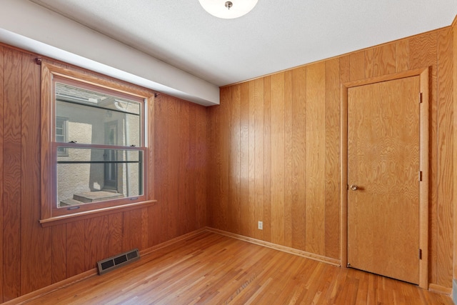 unfurnished room with wood finished floors and wooden walls