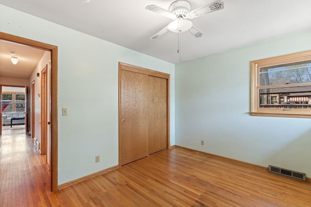 unfurnished bedroom with wood finished floors, baseboards, a closet, and a ceiling fan