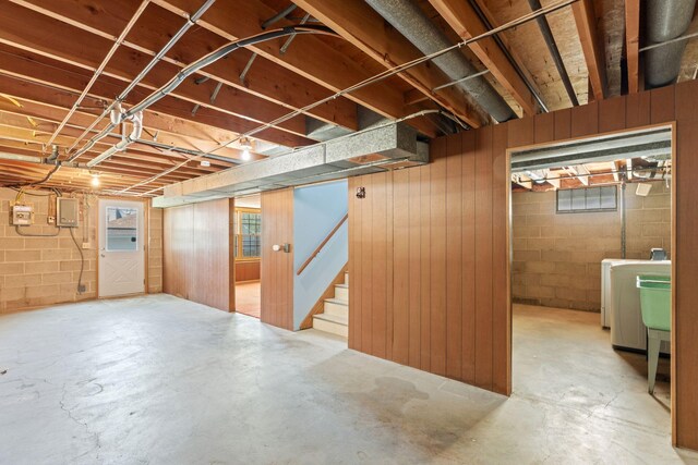basement featuring washer / clothes dryer, electric panel, stairway, and concrete block wall