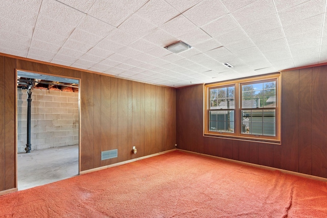 carpeted empty room featuring wooden walls