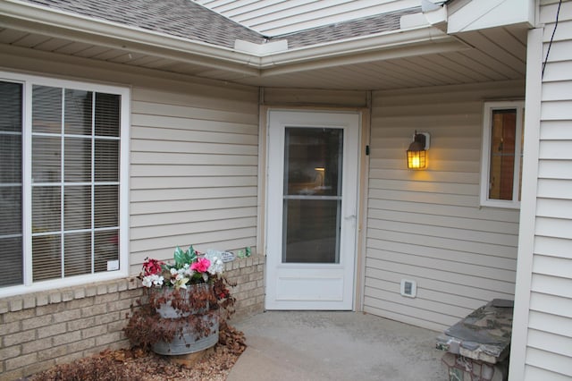 view of exterior entry with roof with shingles