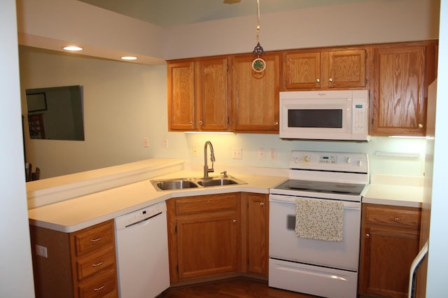 kitchen featuring white appliances, a sink, a peninsula, light countertops, and recessed lighting