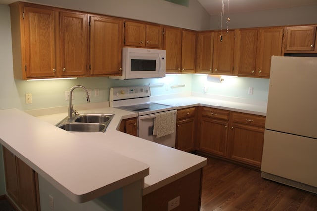 kitchen featuring white appliances, a sink, brown cabinetry, a peninsula, and lofted ceiling