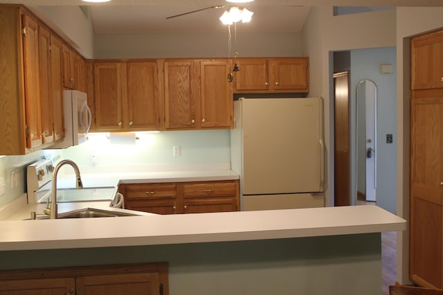 kitchen with a sink, white appliances, light countertops, and brown cabinetry