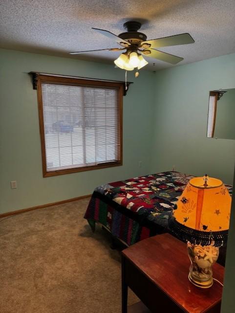 bedroom featuring a textured ceiling, carpet floors, ceiling fan, and baseboards