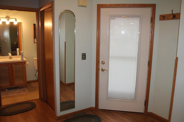doorway with a sink, wood finished floors, and baseboards