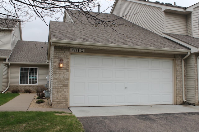 view of front of property featuring roof with shingles, driveway, a garage, and brick siding