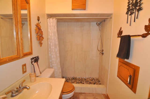full bathroom featuring toilet, a tile shower, and vanity