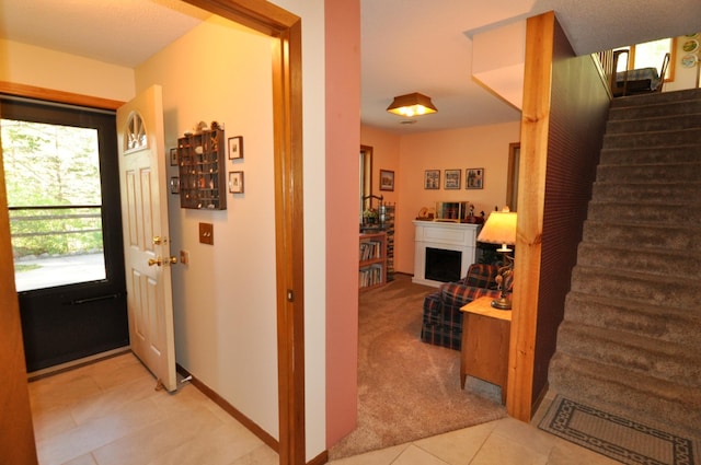 entrance foyer with stairway, light tile patterned floors, and light colored carpet