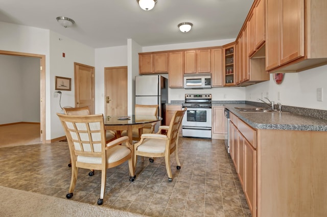 kitchen featuring stainless steel appliances, a sink, dark countertops, and glass insert cabinets