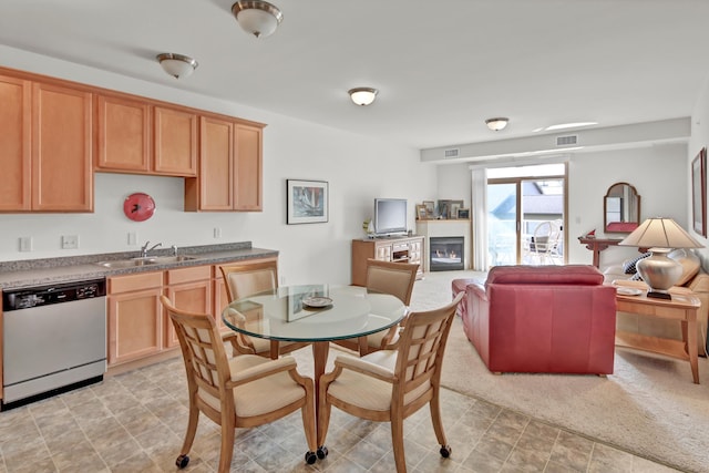 kitchen with dishwasher, a sink, a glass covered fireplace, and open floor plan