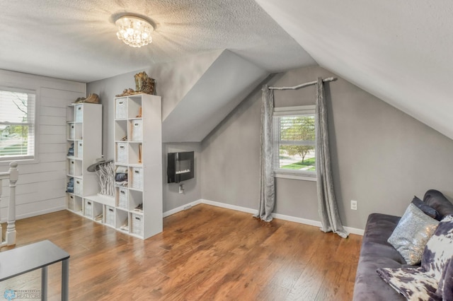 101 5th St NE, Barnesville, MN 56514 - additional living space with a textured ceiling, wood finished floors, lofted ceiling, baseboards, and a chandelier