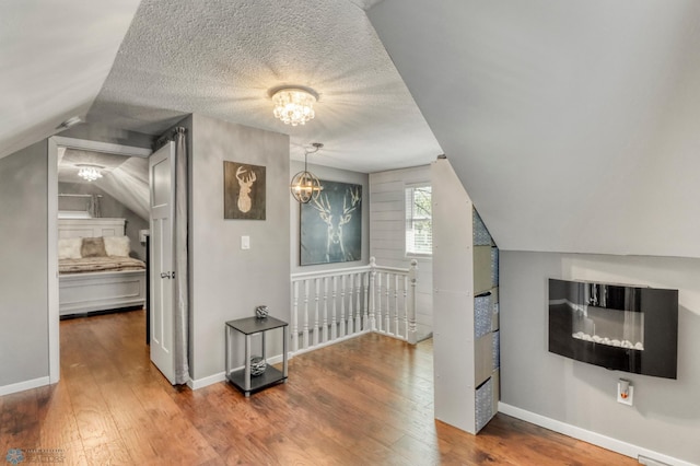 101 5th St NE, Barnesville, MN 56514 - additional living space featuring a chandelier, wood finished floors, lofted ceiling, baseboards, and a textured ceiling