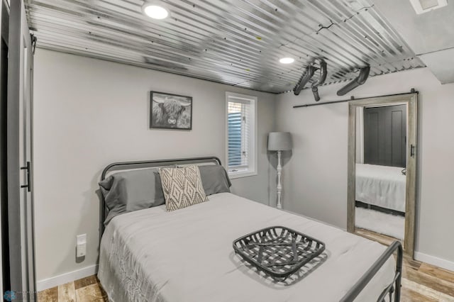101 5th St NE, Barnesville, MN 56514 - bedroom featuring a barn door, baseboards, and light wood-type flooring
