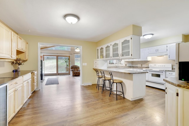 W12798 State Road 35, Prescott, WI 54021 - kitchen featuring white electric range oven, a breakfast bar, under cabinet range hood, light wood-type flooring, and glass insert cabinets
