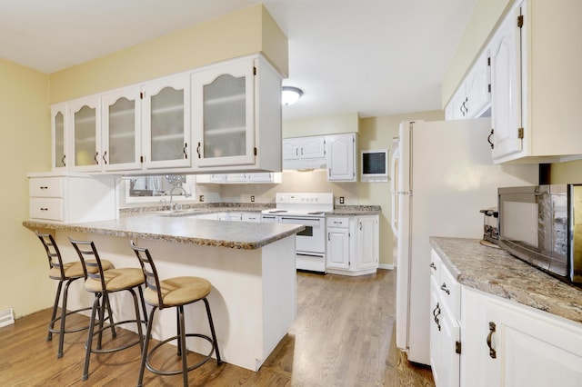 W12798 State Road 35, Prescott, WI 54021 - kitchen with white appliances, a breakfast bar, glass insert cabinets, white cabinetry, and a peninsula