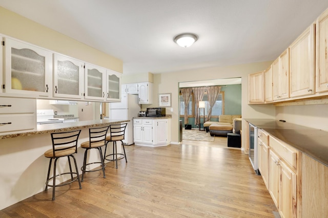 W12798 State Road 35, Prescott, WI 54021 - kitchen featuring a kitchen breakfast bar, light wood-type flooring, freestanding refrigerator, glass insert cabinets, and beverage cooler