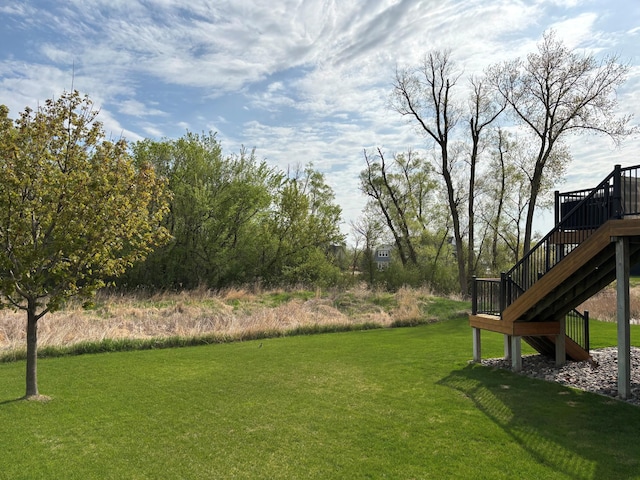 view of grassy yard featuring stairs and a wooden deck