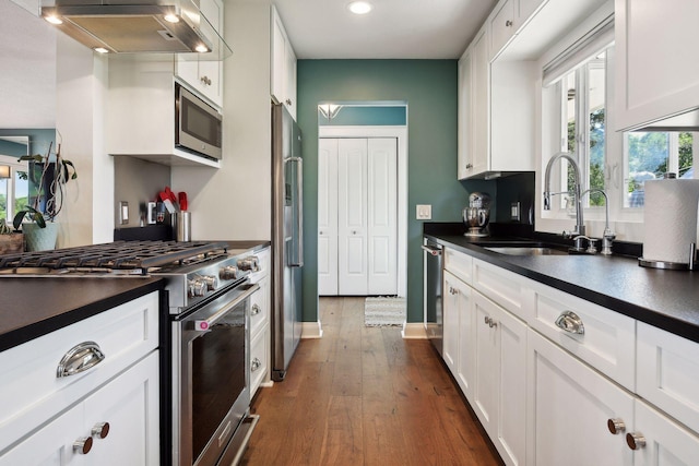 kitchen with stainless steel appliances, a sink, extractor fan, dark countertops, and recessed lighting