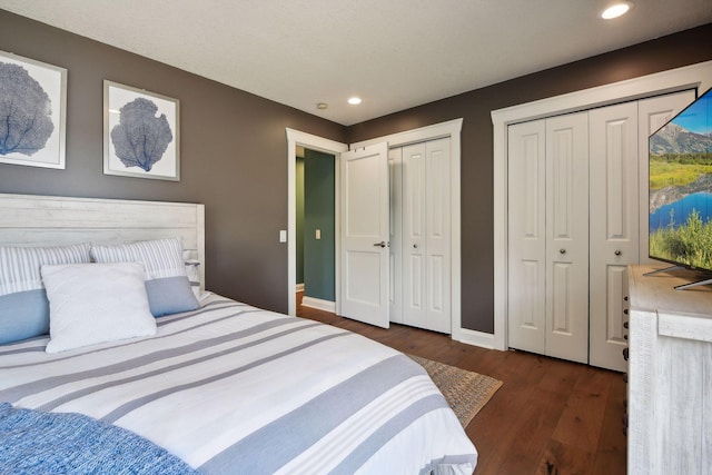 bedroom with two closets, wood finished floors, recessed lighting, and baseboards