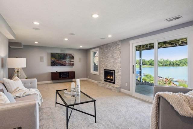 living area featuring light carpet, recessed lighting, baseboards, and a stone fireplace