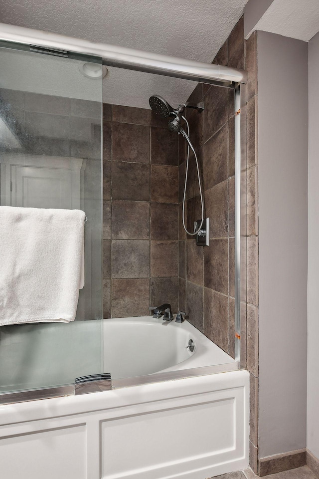 full bath with bath / shower combo with glass door and a textured ceiling