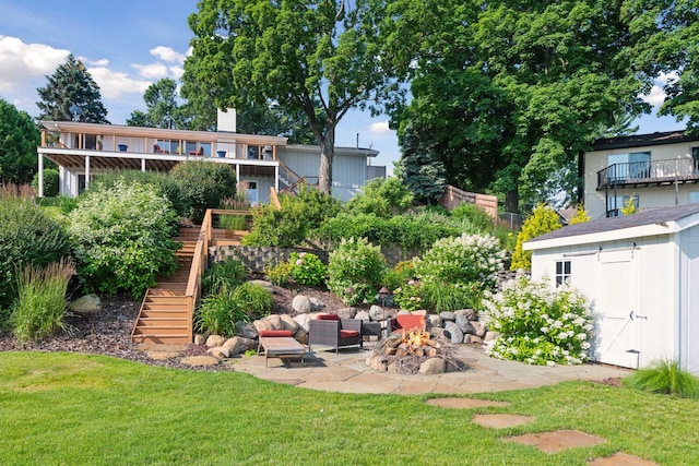 view of grassy yard with stairs, a fire pit, a patio, an outdoor structure, and a shed