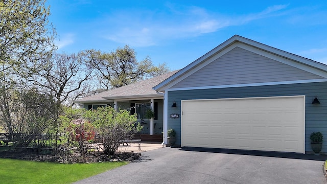 ranch-style house featuring fence, a garage, driveway, and a shingled roof