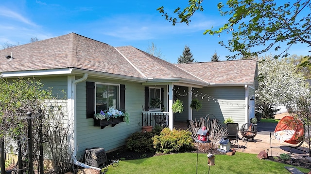 back of property with a yard and a shingled roof