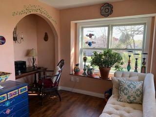 office space with healthy amount of natural light, dark wood-type flooring, arched walkways, and baseboards