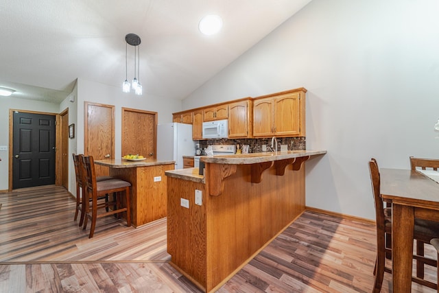 17081 Pheasant Meadow Ln SW, Prior Lake, MN 55372 - kitchen featuring white appliances, a peninsula, light wood finished floors, tasteful backsplash, and a kitchen breakfast bar