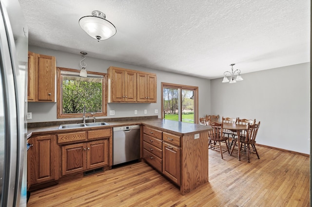 7349 Variolite Dr NW, Stanford Twp, MN 55398 - kitchen featuring appliances with stainless steel finishes, a sink, a peninsula, dark countertops, and a textured ceiling