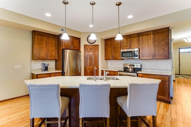 8713 9th Pl N, Lake Elmo, MN 55042 - kitchen with stainless steel appliances, light wood finished floors, decorative backsplash, hanging light fixtures, and recessed lighting