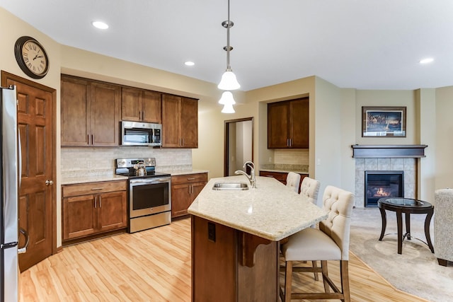 8713 9th Pl N, Lake Elmo, MN 55042 - kitchen featuring stainless steel appliances, a breakfast bar, light wood-style flooring, tasteful backsplash, and decorative light fixtures
