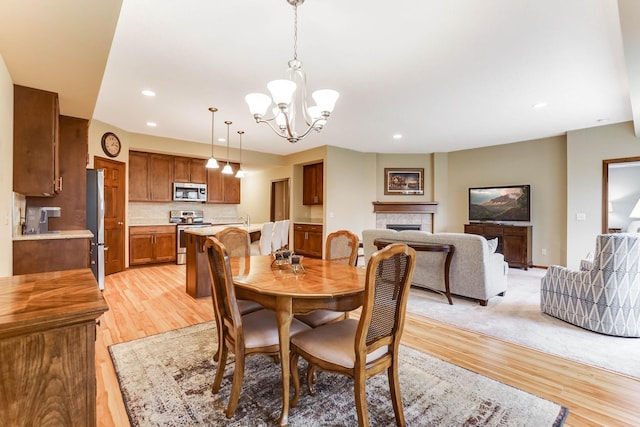 8713 9th Pl N, Lake Elmo, MN 55042 - dining room with light wood-style floors, a chandelier, a tile fireplace, and recessed lighting