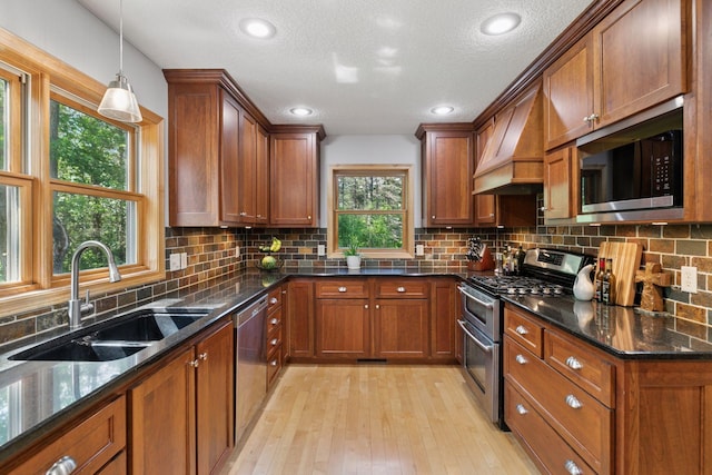 14530 Jonathan Carver Pkwy, Carver, MN 55315 - kitchen featuring appliances with stainless steel finishes, custom range hood, brown cabinets, light wood-style flooring, and a textured ceiling