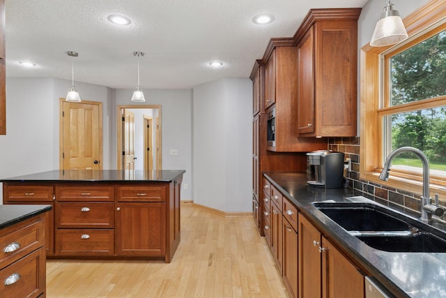 14530 Jonathan Carver Pkwy, Carver, MN 55315 - kitchen featuring a sink, brown cabinets, light wood-style floors, tasteful backsplash, and pendant lighting