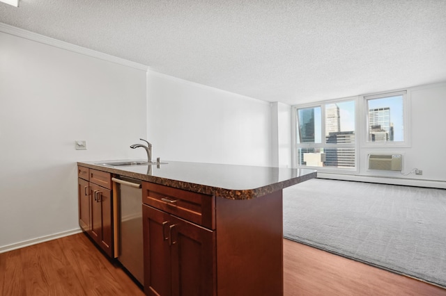 kitchen with a sink, a textured ceiling, a peninsula, dishwasher, and light wood finished floors