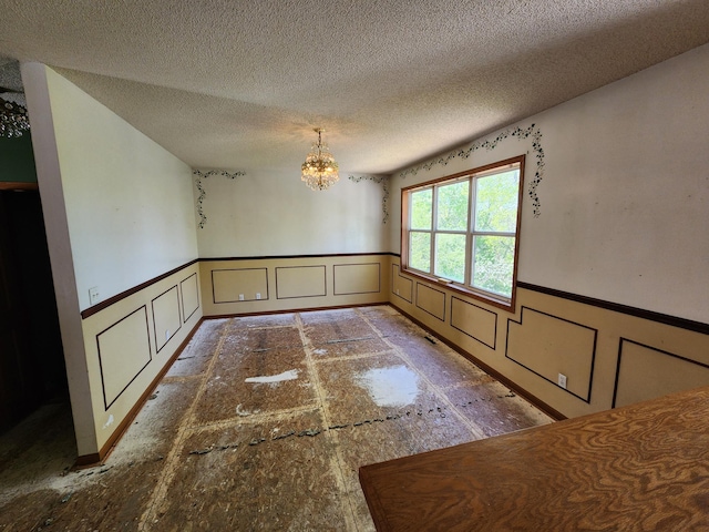 3458 Savannah Ave, White Bear Lake, MN 55110 - unfurnished dining area with a decorative wall, a wainscoted wall, a chandelier, and a textured ceiling